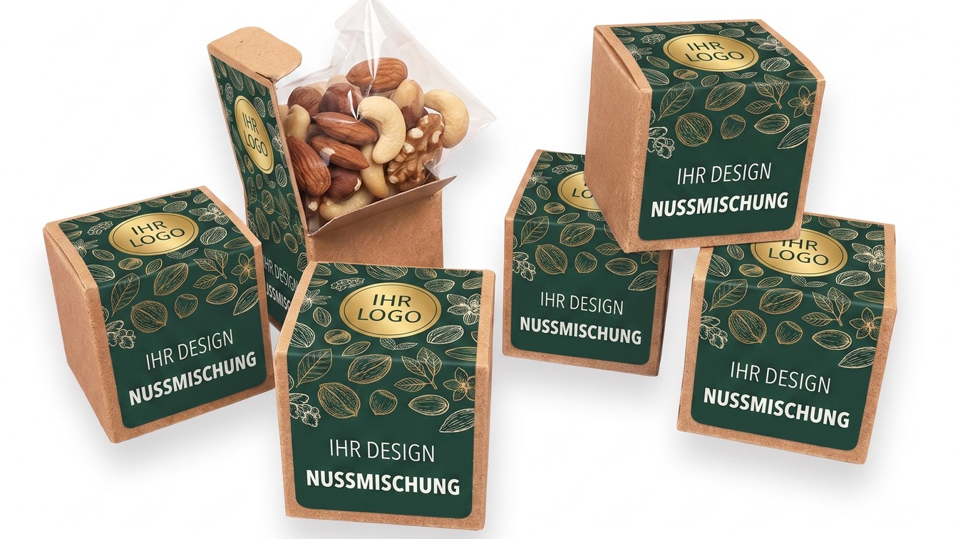 Mehrere Werbe-Würfel aus Kraftkarton mit grün-goldenem Etikett, einer geöffnet mit einem Zellglas-Beutel voller Nusskerne